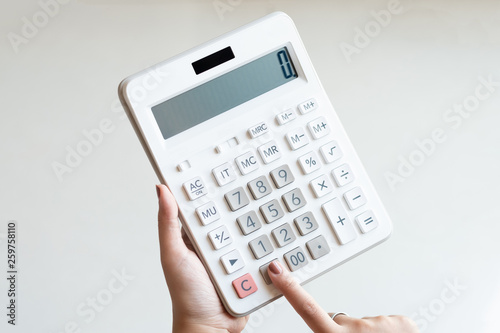 Businesswoman using a white calculator to calculate the value of business financial