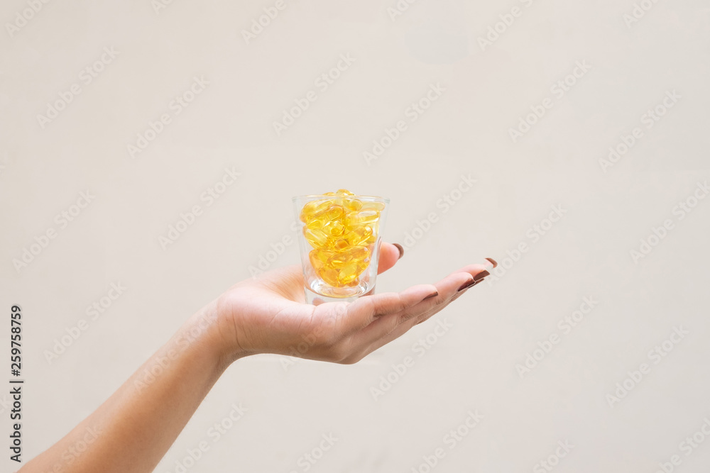 Young woman holding a small glass with yellow pills inside Young woman holding a small glass with yellow pills inside