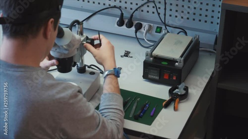 Electronics Research and Service Organization. The engineer sets up the microscope to diagnose the motherboard. Detection of microcracks, moisture ingress, other malfunctions