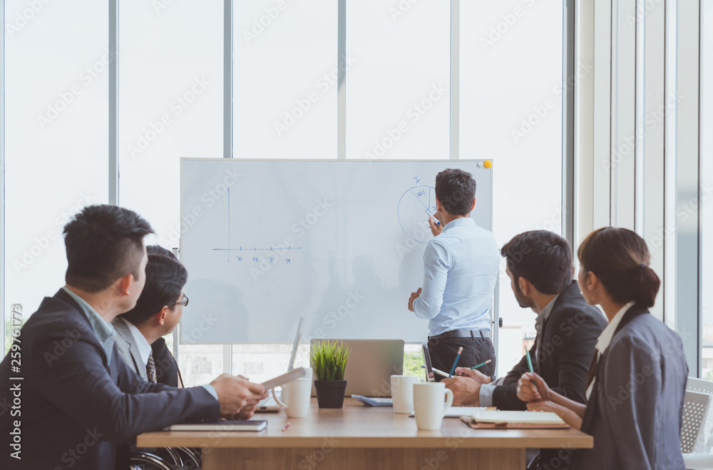 Businessman leader writing on the whiteboard present business marketing graph while meeting with colleagues in office.Business Team Meeting Presentation,Conference Planning Business Concept Businessman leader writing on the whiteboard present business marketing graph while meeting with colleagues in office.Business Team Meeting Presentation,Conference Planning Business Concept