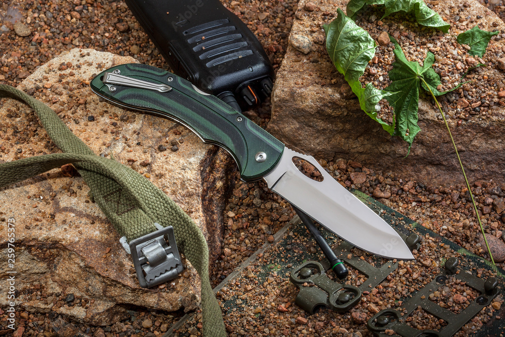 Obraz premium Folding knife and walkie-talkie are on the rocks