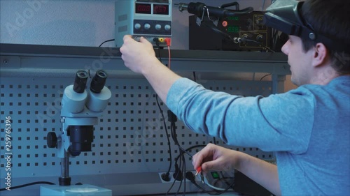 Diagnostics of electronic components. The engineer uses special equipment, connects negative black and positive red wires to the device
