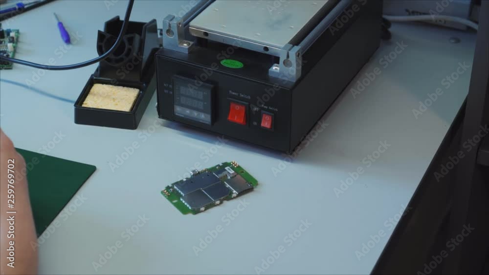 Service repair shop. Laptop charger maintenance and renovation. Worker hands soldering wires on disassembled broken damaged part Service repair shop. Laptop charger maintenance and renovation. Worker hands soldering wires on disassembled broken damaged part