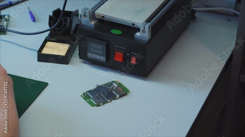 Service repair shop. Laptop charger maintenance and renovation. Worker hands soldering wires on disassembled broken damaged part