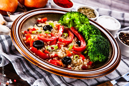 Groats with vegetables on wooden table