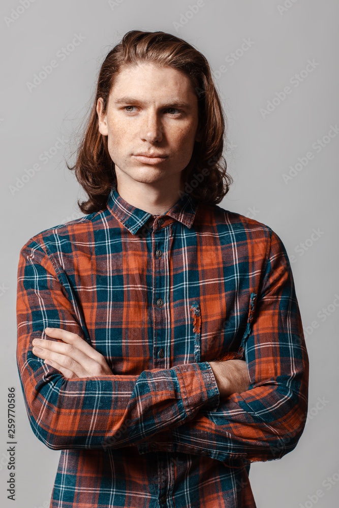 Portrait of a man with long hair and freckles, dressed in a checkered shirt Portrait of a man with long hair and freckles, dressed in a checkered shirt