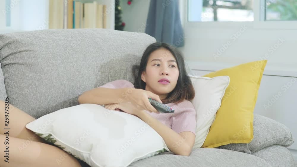 Young Asian teenager woman watching TV at home, female feeling happy lying on sofa in living room. Lifestyle woman relax in morning at home concept. Young Asian teenager woman watching TV at home, female feeling happy lying on sofa in living room. Lifestyle woman relax in morning at home concept.