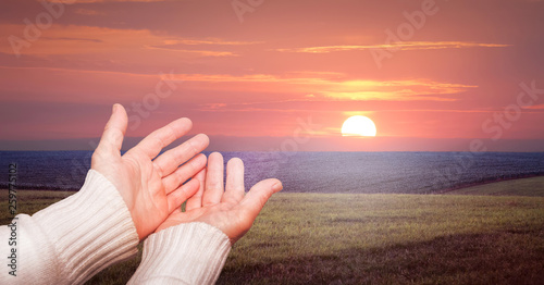 A woman stretch your arms in prayer to the sky during the sunset_