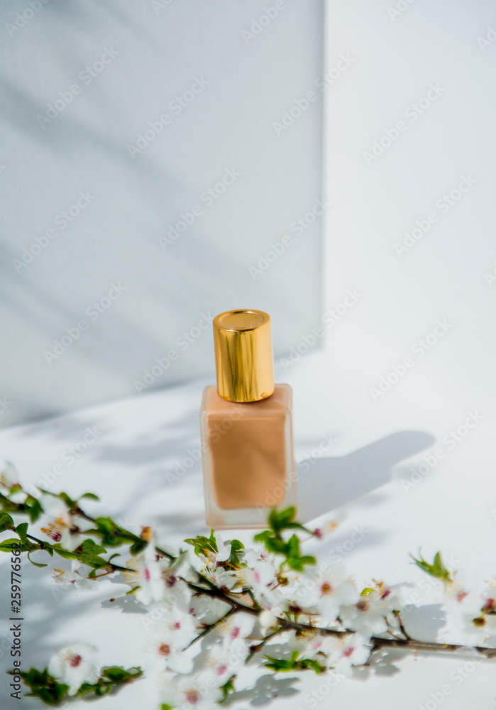 Foundation cream in golden bottle and branch of blossom cherry tree. Foundation cream in golden bottle and branch of blossom cherry tree.