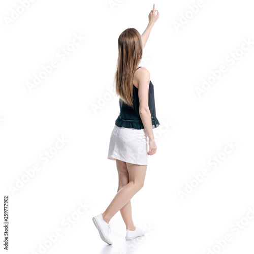 Woman in white skirt and black showing pointing on white background isolation, back view © Kabardins photo