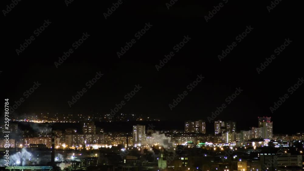 Night city skyline timelapse. Top aerial panoramic view of modern city from tower rooftop. Road junction traffic. Lights flicker in windows. Residential flats,factory pipes with smoke Night city skyline timelapse. Top aerial panoramic view of modern city from tower rooftop. Road junction traffic. Lights flicker in windows. Residential flats,factory pipes with smoke