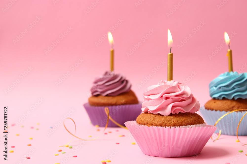 Delicious cupcakes with candles on a colored background. Festive background, birthday Delicious cupcakes with candles on a colored background. Festive background, birthday
