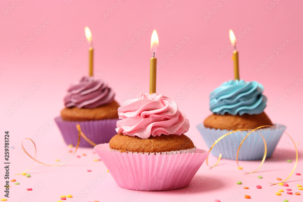 Delicious cupcakes with candles on a colored background. Festive background, birthday Delicious cupcakes with candles on a colored background. Festive background, birthday