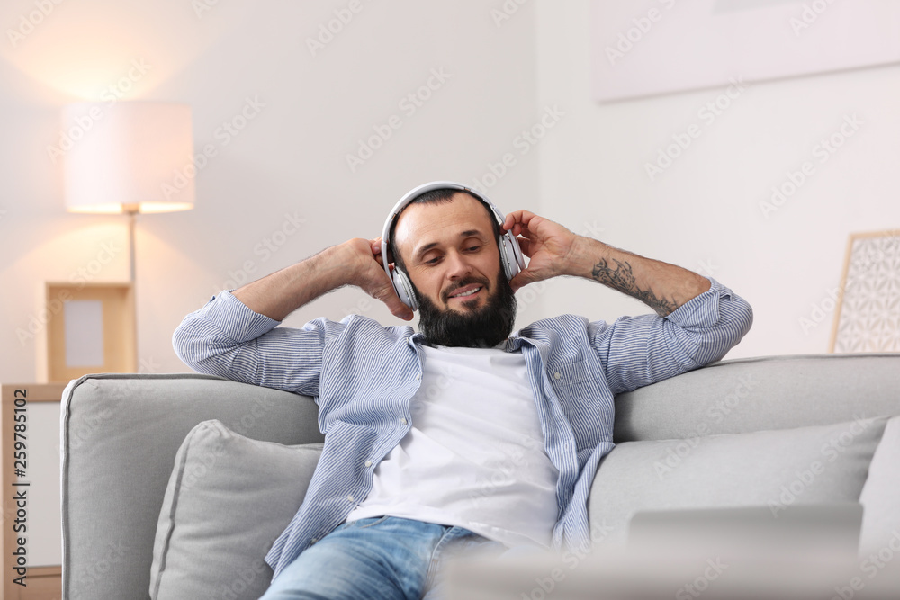 Mature man with headphones resting on sofa at home