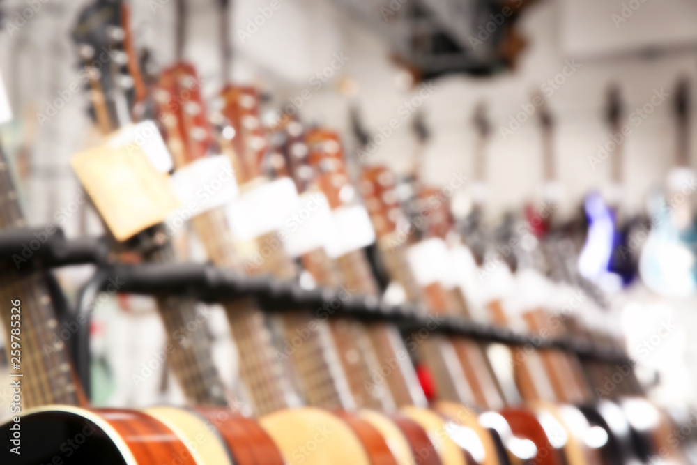 Row of different guitars in music store, blurred view Row of different guitars in music store, blurred view