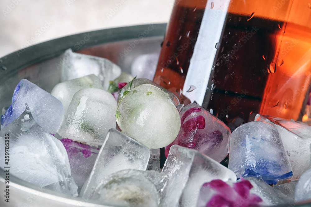 Floral ice cubes and bottle of champagne in bucket, closeup Floral ice cubes and bottle of champagne in bucket, closeup