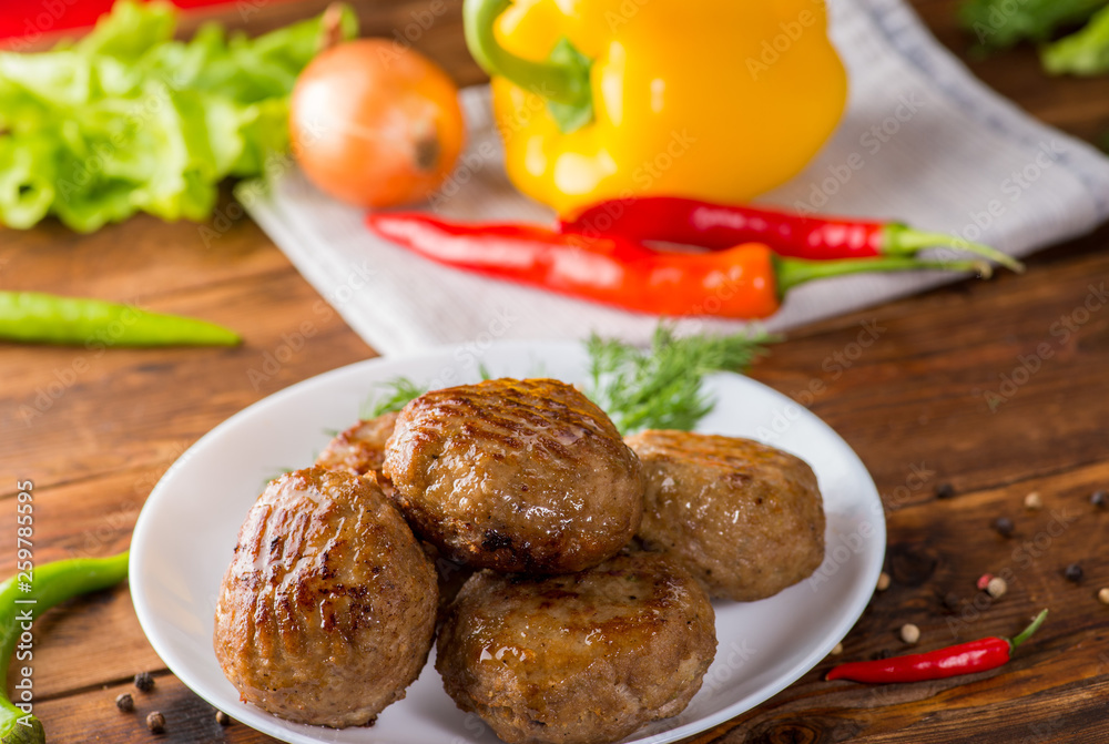 cutlets on a white plate on the background of vegetables and greens. Wooden table and home view cutlets on a white plate on the background of vegetables and greens. Wooden table and home view