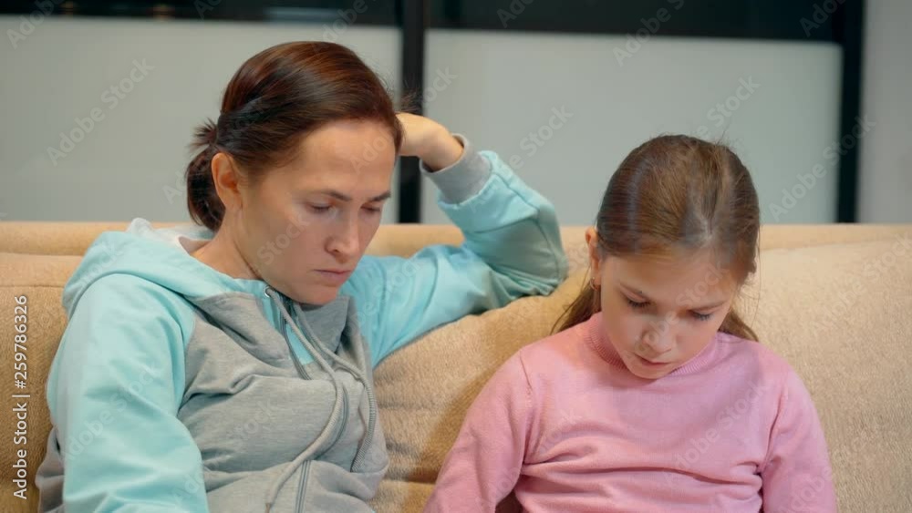 Mother with little daughter having fun and read the book together on the sofa at home. 10 year old girl with her mother reading a book. Love of family and concept Mother with little daughter having fun and read the book together on the sofa at home. 10 year old girl with her mother reading a book. Love of family and concept