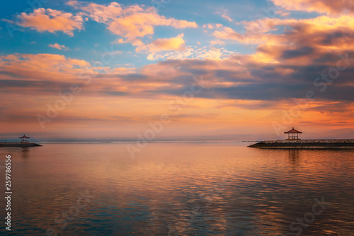 Bali Sanur at sunrise on the beach. Beautiful calm water with 2 temples on a breakwater. Great reflection in the water with backlighting and great clouds © Jan