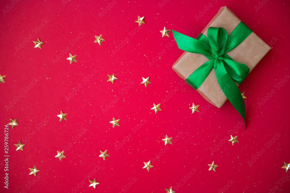 gift box on golden sequins and stars red background. Top view, flat lay. Copyspace for text. Festive holiday background. gift box on golden sequins and stars red background. Top view, flat lay. Copyspace for text. Festive holiday background.