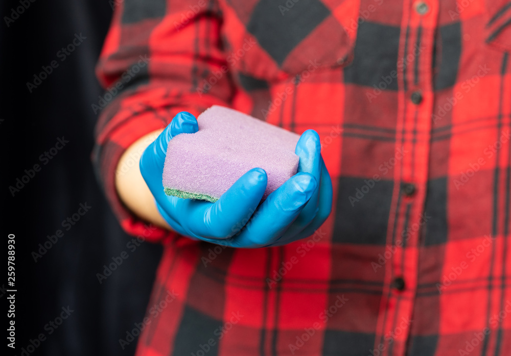 Fototapeta premium Kitchen sponge in the hand of the girl. Girl's hand in a hygienic glove.