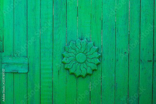 Texture of old fance, painted light-green and flower from wood in the centre.