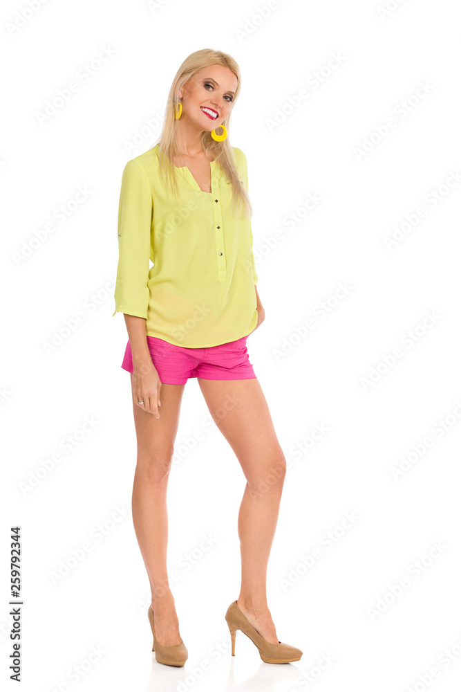 Fototapeta premium Smiling Beautiful Blond Woman In Vibrant Clothes And High Hells Is Standing And Looking At Camera