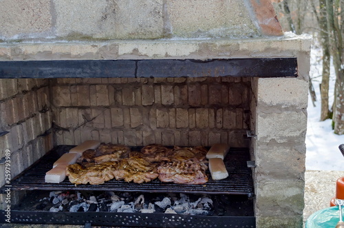 Part of stove brick masonry for barbecue with juicy steaks cooking on a grill over embers, town Zavet, Bulgaria, Europe
