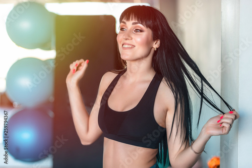Beautiful young girl fitness instructor in gym looking away and smiling