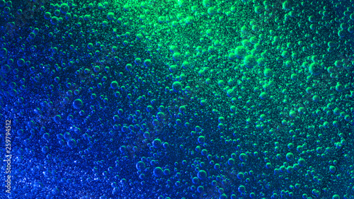 Blue illuminated liquid with impressive quantity of sparkling air bubbles.