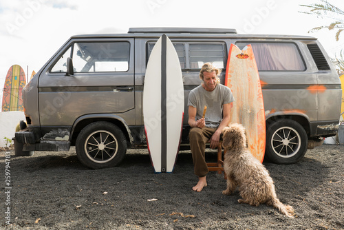 Man standing near surf boards and van photo