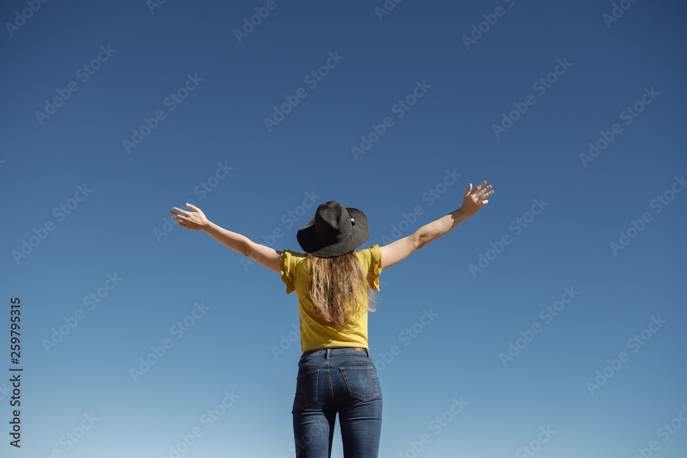 From below woman standing with hands apart against blue cloudless sky From below woman standing with hands apart against blue cloudless sky