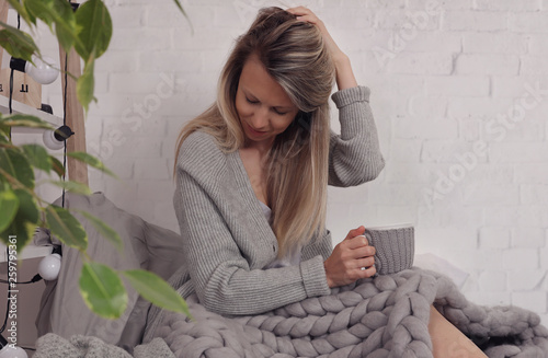 Cozy Woman covered with warm soft merino wool blanket relaxing at home. Comfort lifestyle.