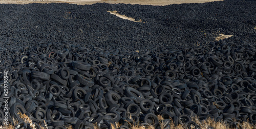 Huge pile of old auto tires between meadow photo