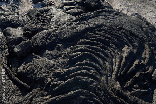 Closeup texture of dark rough rock in sunlight