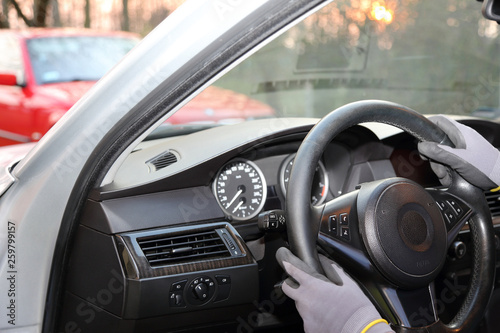 Dłonie kierowcy w rękawiczkach na kierownicy samochodu osobowego.