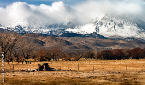 storm clouds clearing after snowfall in the eastern Sierra Nevada mountains in California farmland in the foreground photo