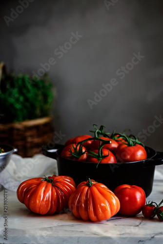 Ripe fresh tomatoes in pot on table photo