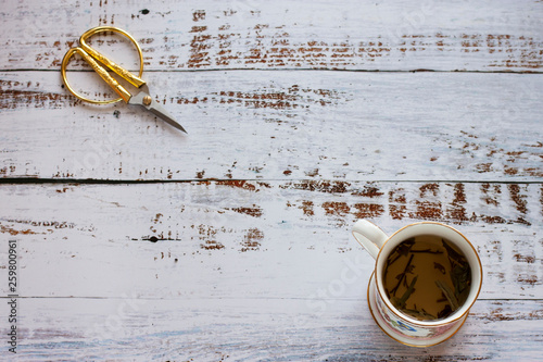 Cup and scissors on white wooden background. photo