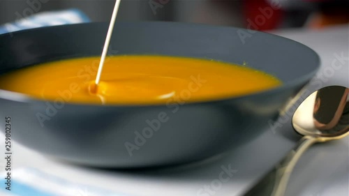 Adding cream to pumpkin soup cream. Slow motion