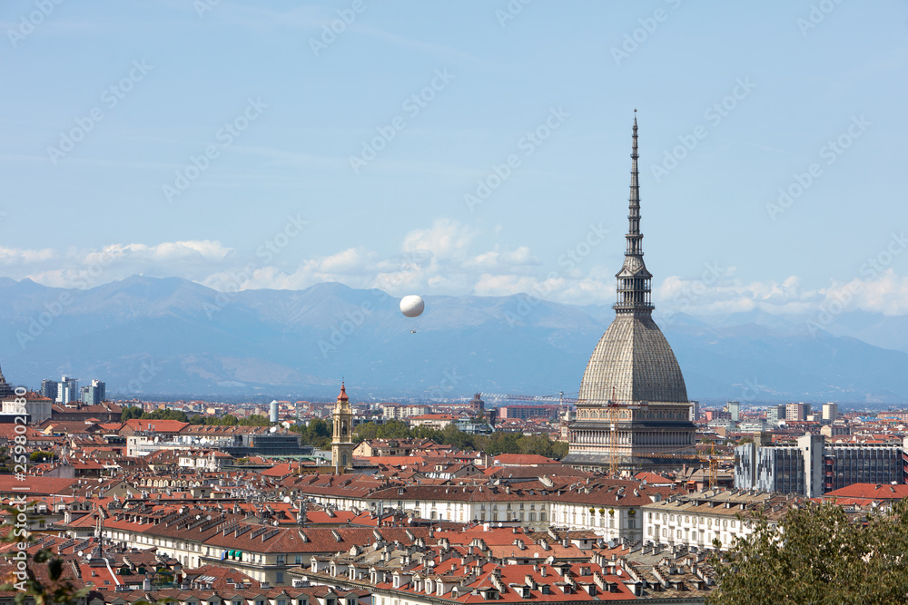 Turin city rooftops, Mole Antonelliana tower and hot air balloon in a sunny summer day in Italy
