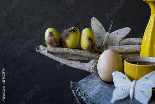 vintage Easter still life with yellow eggs, butterfly, cup and saucer and twig photo