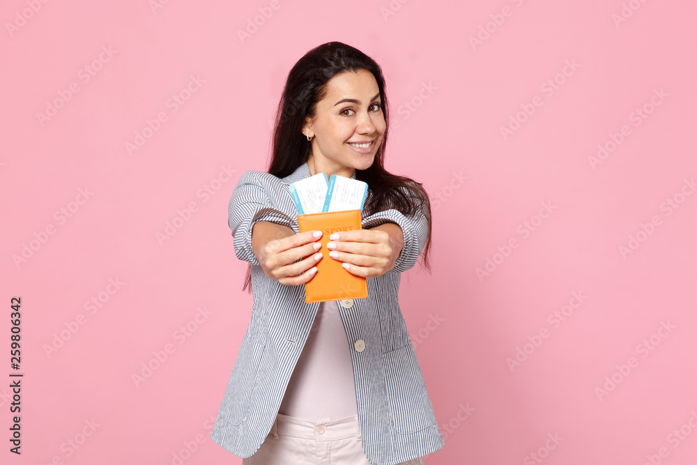 Pretty smiling young woman in striped jacket holding passport, boarding pass ticket isolated on pink pastel wall background in studio. People sincere emotions, lifestyle concept. Mock up copy space. Pretty smiling young woman in striped jacket holding passport, boarding pass ticket isolated on pink pastel wall background in studio. People sincere emotions, lifestyle concept. Mock up copy space.