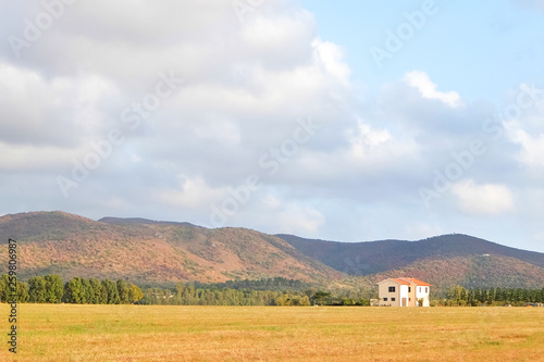 Beautiful agricultural landscape with hills and cloudy sky in background. Sunny day in italian countryside.
