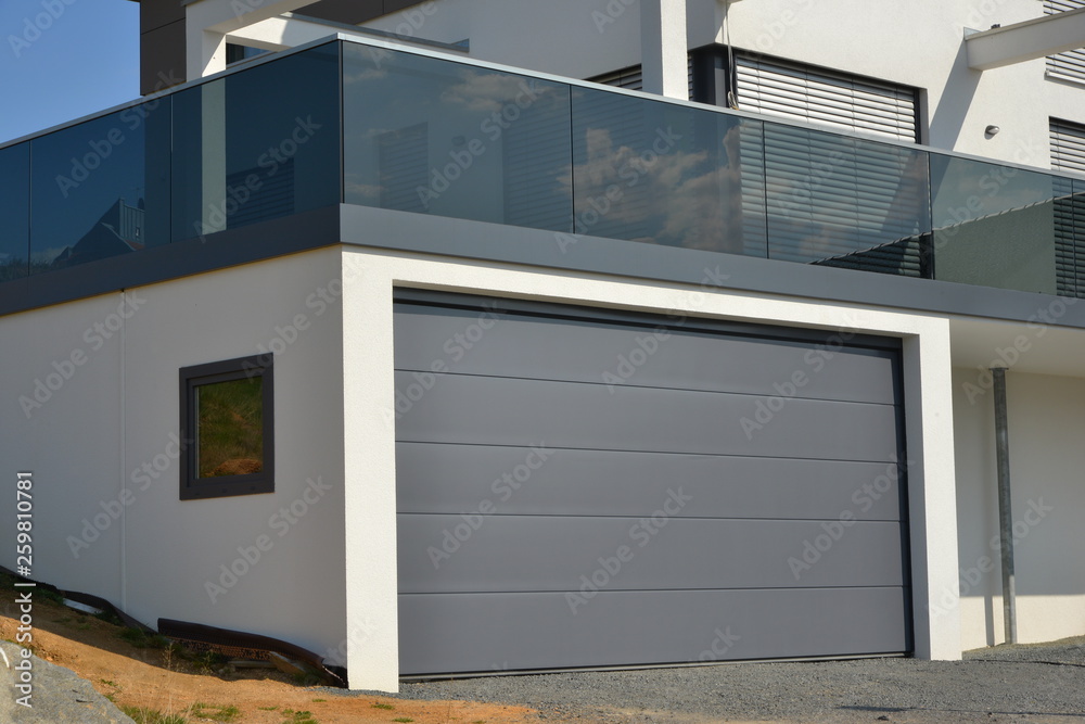 Moderner Balkon mit Rauchglas-Sichtschutz und moderner Garage mit  Automatik-Tor Photos | Adobe Stock