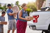 hispanic family moving boxes out of pickup truck into house