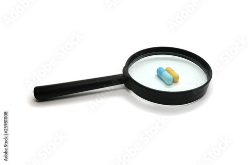 Magnifier increases medication pills to treat isolated on white background.