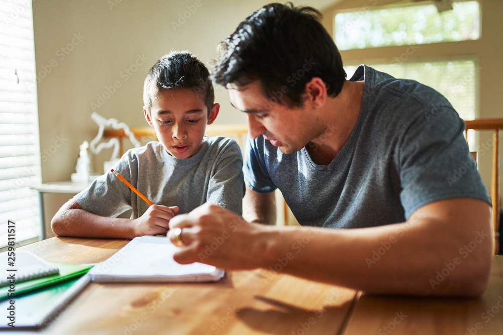 Naklejka premium father helping son with homework on table at home