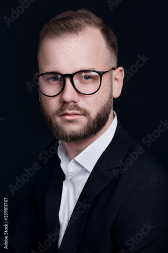 Handsome young businessman in glasses on black background