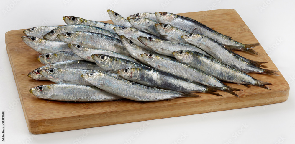 Fresh raw sardines on wooden cutting board Fresh raw sardines on wooden cutting board